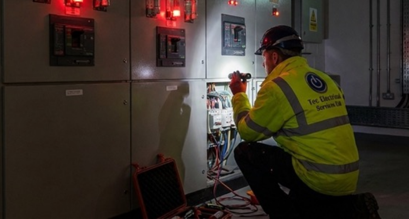 Tech Electrical engineer carrying out emergency electrical diagnostics at a control panel
