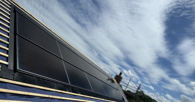 Solar panels being installed on a new-build roof under a blue sky