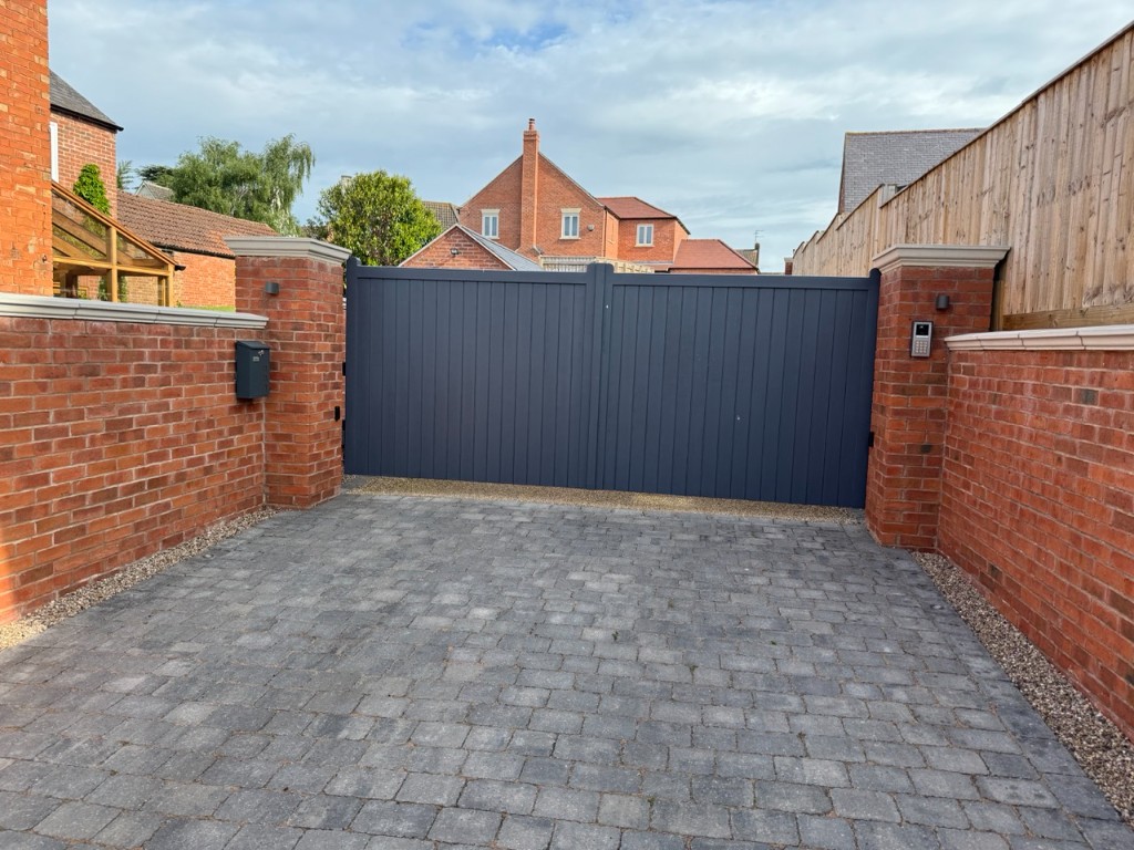 Automated driveway gates with brick pillars, pillar lights, and keypad entry