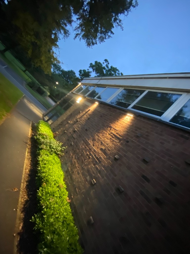 Brick communal building facade with exterior downlights at dusk