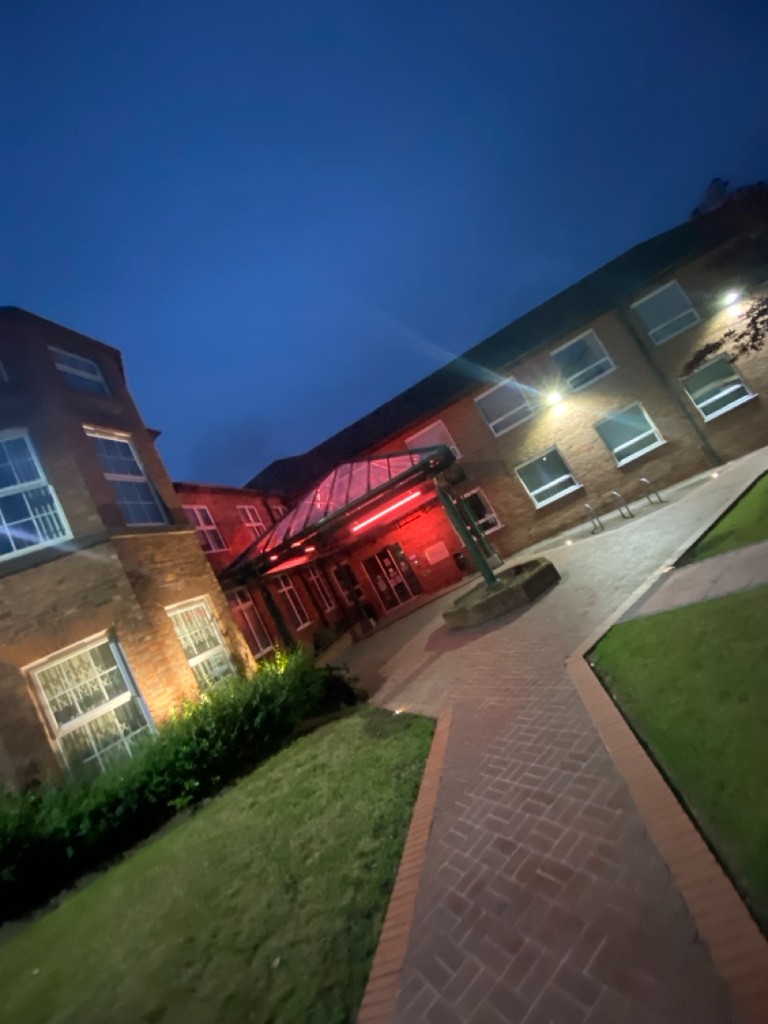 Fairfax communal building entrance with illuminated glass canopy at dusk