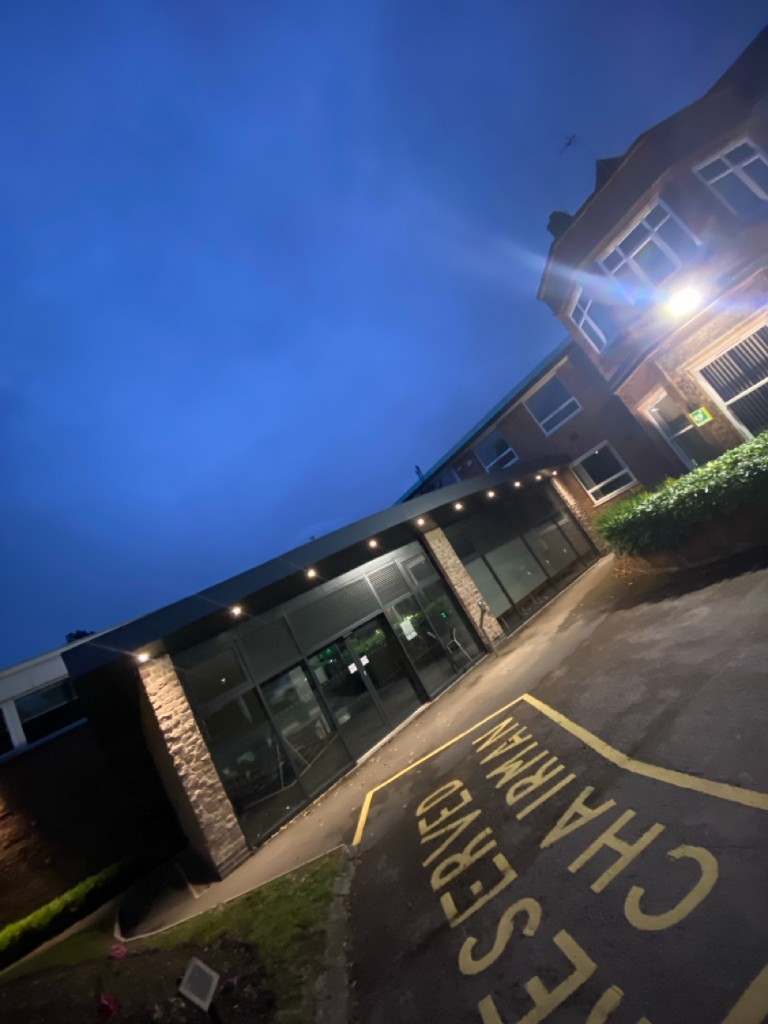 Modern glass entrance extension with stone pillar and exterior spotlights