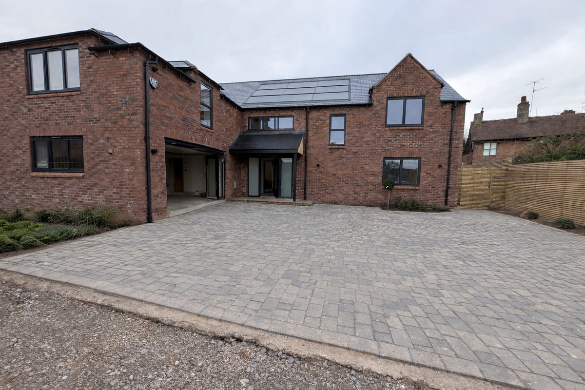 Front elevation of luxury brick new build with solar panels and paved driveway