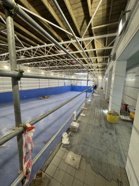 Swimming pool hall with truss lighting and blue tiled pool