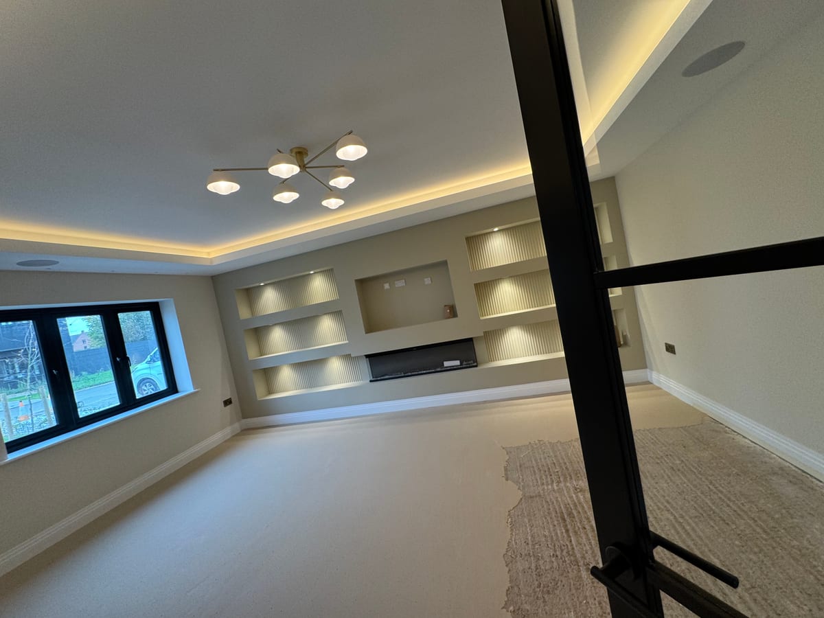 Living room media wall with shelf lighting, chandelier, and electric fireplace